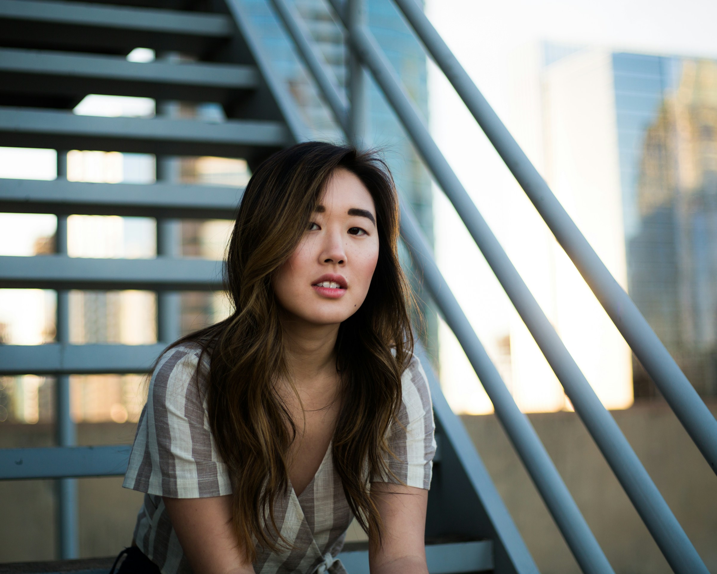 Woman seated beside a modern outdoor staircase