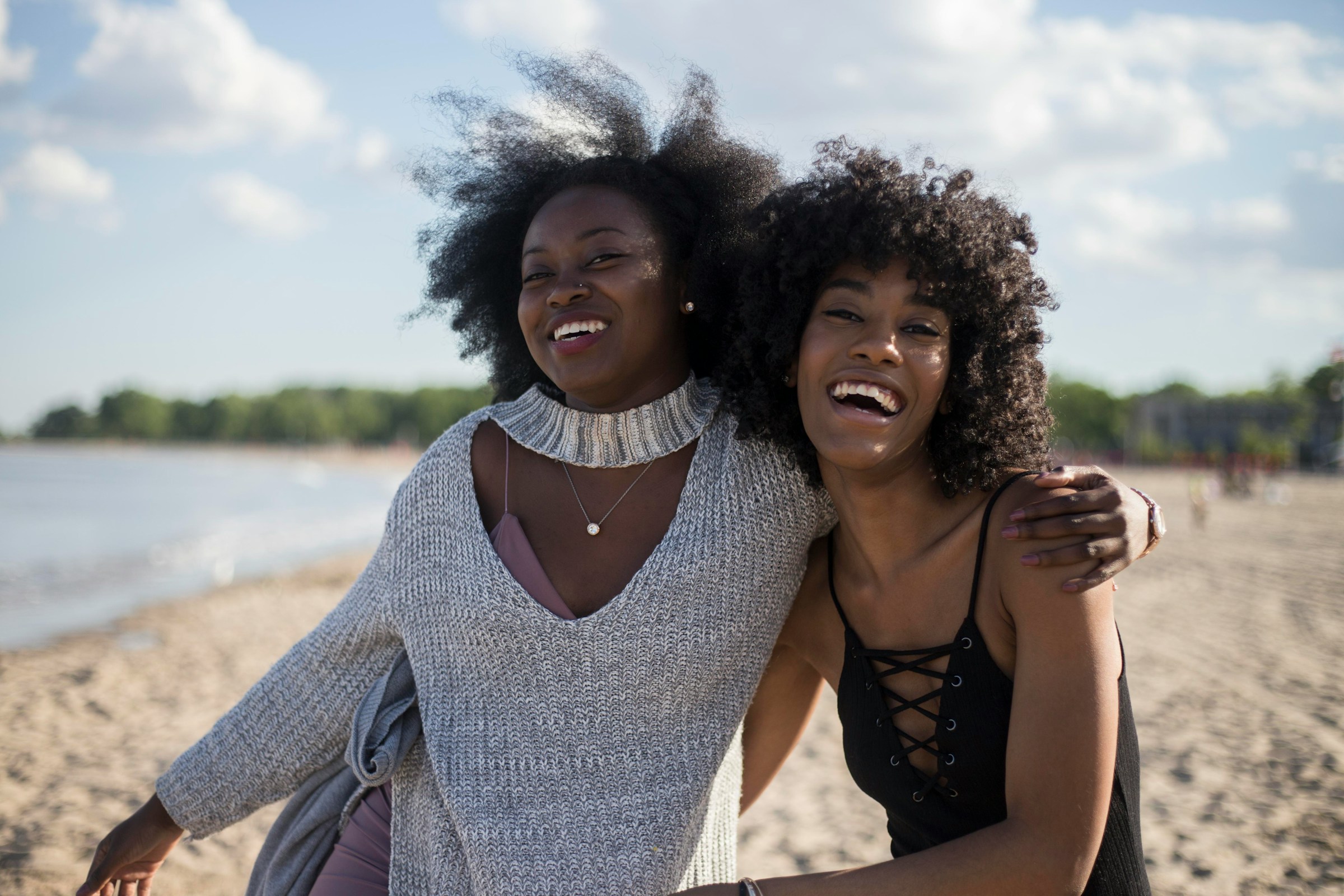 Two women smiling together outdoors by the water